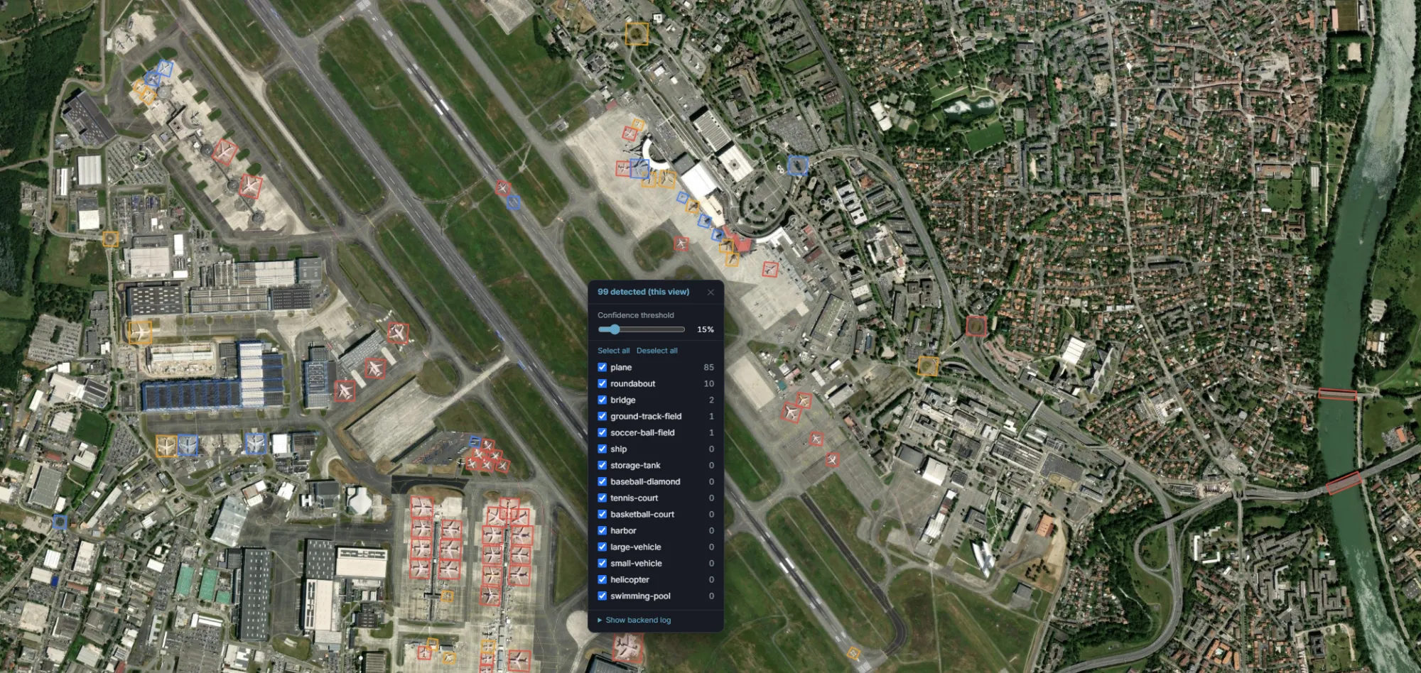 Object detection results over an airport: 99 objects detected and outlined on the map — 85 planes, 10 roundabouts, 2 bridges, a ground-track field and a soccer-ball field — with a confidence-threshold slider and a per-class checklist covering all 15 supported classes.